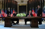 Le leader nord-coréen Kim Jong Un (g) et le président américain Donald Trump (d) signent un document en présence du secrétaire d'Etat américain Mike Pompeo et de la soeur du dirigeant nord-coréen Kim Yo Jong, le 12 juin 2018 à l'hôtel Capella, sur l'île de Sentosa, à Singapour