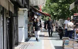 Des Iraniens passent devant une boutique sur la place Enghelab (Révolution), à Téhéran, le 24 juin 2025