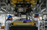 Des ouvriers travaillent sur une ligne de production de l'usine Neolix qui fabrique de petits véhicules utilitaires autonomes pour le transport de colis en ville, le 4 décembre 2025 à Yancheng dans la province chinoise du Jiangsu