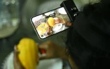 Nagireddy Sriramyachandra filme avec un téléphone ses gestes pendant qu'elle coupe une mangue pour entraîner un futur robot dopé à l'IA, le 15 mai 2026 à Madras, en Inde