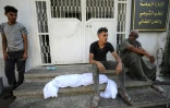 Un homme attend avec le cadavre d'un enfant enveloppé dans un drap devant un hôpital, après un bombardement israélien  contre le quartier de Shuja'iyya, dans l'est de Gaza-ville, le 4 novembre 2023