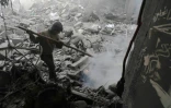 Un garçon tente d'éteindre un feu dans les décombres d'un bâtiment après un bombardement du régime syrien sur Douma, une ville de la Ghouta orientale encore tenue par les rebelles, le 19 mars 2018