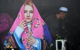 Un homme nettoie un cliché de la photographe afghane Fatimah Hossaini exposé le 3 juin 2022 à La Gacilly (Morbihan) dans le cadre de la 19e édition du festival photo en plein air de la commune