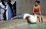 Un homme se rafraîchit en plongeant sa tête dans la fontaine de Piazza Venezia à Rome, le 26 juin 2005, jour de canicule