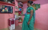 Manda Sunil Bhave, éligible à la relocalisation dans le cadre d'un projet de rénovation urbaine, regarde la télévision chez elle à Dharavi, un bidonville de Bombay, le 9 juillet 2025 en Inde