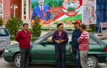 Des hommes bavardent devant un portrait du président du Tadjikistan, Emomali Rakhmon, dans le district de Khourosson, le 26 mars 2024