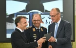 Le chancelier allemand Friedrich Merz (d) et le président français Emmanuel Macron écoutent les explications du commandant de l'escadre aérienne tactique 31 "Boelcke", le colonel Rene Diegeler, à leur arrivée à la base aérienne de Nörvenich, dans l'ouest de l'Allemagne, le 17 juillet 2026