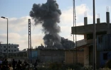 De la fumée d'une frappe israélienne alors que des Palestiniens marchent le long d'une route utilisée pour atteindre un point de distribution d'aide de la Fondation humanitaire de Gaza (GHF), près du camp de réfugiés de Nousseirat, dans le centre de la bande de Gaza, le 25 juin 2025