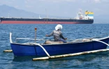 Un pêcheur passe à proximité du navire Sara Sky, battant pavillon sierra-léonais et transportant du pétrole brut russe, à l'ancrage au port de Limay, dans la province de Bataan, le 26 mars 2026 aux Philippines