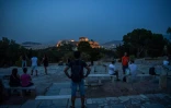 Des Athéniens contemplent, le 17 mai au soir, l'Acropole fermé depuis le début du confinement et qui devaient rouvrir le lendemain matin