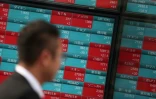 Un homme près d'un panneau indiquant les cours de Bourse, à Tokyo, le 20 novembre 2018
