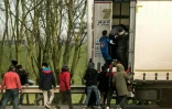 Des migrants montent dans un poids-lourd le 17 décembre 2016 à Calais pour se rendre clandestinement en Grande-Bretagne