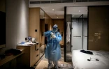 Un membre du personnel médical se prépare à faire un test au Covid-19 à un client de l'hôtel dans sa chambre, dans un hôtel du district de Yanqing à Pékin, le 1er février 2022, en prévision des Jeux olympiques d'hiver de Pékin 2022