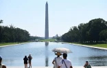 Deux personnes se protègent du soleil sous un parapluie à Washington, le 23 juillet 2022, alors que la température pourrait atteindre 38 degrés Celsius