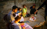 Mosaab Abou Toha (G) lit des livres à des enfants dans le jardin d'une maison de Beit Lahya dans le nord de Gaza le 20 février 2017