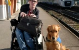 Kevin Fermine, en fauteuil roulant depuis son plus jeune âge, pose avec son chien Djembe le 16 mars 2017 à la gare de Toulouse-Saint-Agne
