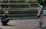 Des touristes portent des masques de protection, le 23 février 2020, devant un temple de Bangkok