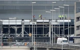 Des ouvriers marchent sur le toit de l'aéroport de Bruxelles à Zaventem le 23 mars 2016 au lendemain des attentats terroristes dans la capitale belge