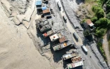 Vue aérienne de véhicules circulant devant des maisons couvertes de boue à la suite de la crue destructrice dans l'Himalaya, le 20 août 2026 soudaines à Baireni, dans le district népalais de Dhading