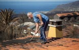 FĂ©lix RodrĂguez, maçon de 61 ans, balaye le sable noir accumulĂ© sur le toit de sa maison, dans la zone des Canaries victime de l'Ă©ruption du volcan