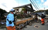 Des pompiers inspectent les dégâts sur des maisons en bois le 2 janvier 2024 à Wajima, dans le département d'Ishikawa, au Japon