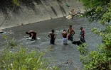 De jeunes Vénézuéliens fouillent toute la journée à mains nues parmi les débris charriés par le courant les eaux sales du fleuve Guaire de Caracas, le 1er février 2018