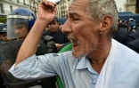 Un manifestant algérien crie des slogans à côté des forces anti-émeutes à Alger, le 24 mai 2019