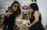 Pimrachaya Worakijmanotham (g) et son amie prennent un selfie avant l'incinération de leur chien bien-aimé Dollar, au temple bouddhiste, à Bangkok, le 14 septembre 2017