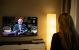 Une femme regarde l'allocution du roi de Suède Carl XVI Gustaf à la télévision, le 5 avril 2020 à Sundbyberg près de Stockholm
