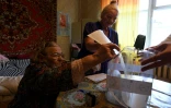 Une personne âgée dépose son bulletin de vote dans une urne apportée à son domicile à Moscou