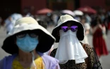 Des femmes se protègent de la chaleur à Pékin, le 16 juin 2023