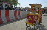 Un vendeur de glaces attend des clients pendant que des employés de l'aéroport de Kaboul font la queue à un point de contrôle pour aller à leur travail, le 4 septembre 2021