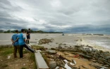 Des habitants regardent un bateau de pêche emporté par les fortes vagues suscitées par la tempête Pabuk dans le sud de la Thaïlande, le 4 janvier 2019