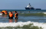 Des migrants tentent de monter à bord d'un bateau de passeurs au large de la plage d'Equihen-Plage, dans le nord de la France, tandis qu'au loin patrouille l'Abeille Normandie, remorqueur français d'urgence, le 23 septembre 2026