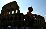Un homme passe devant le Colisée, une bouteille d'eau à la main, le 2 juillet 2025 à Rome