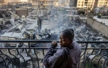 Une femme à son balcon devant des maisons et magasins incendiés après une explosion de gaz dans le quartier d'Embakasi à Nairobi, le 2 février 2024