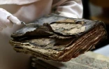 Le père Najeeb Michaeel montre un ancien manuscrit très endommagé au Centre de numérisation des manuscrits orientaux (CNMO) à Erbil, dans le nord de l'Irak, le 1er mars 2018 