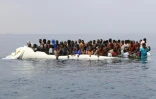 Tandis que leur canot coule, des migrants attendent d'être secourus au large des côtes de Zawiyah en Libye, à l'est de Tripoli, le 20 mars 2017