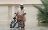 Un homme porte son vélo dans une rue de la capitale omanaise Mascate inondée par des pluies torrentielles provoquées par le cyclone tropical Shaheen, le 3 octobre 2021