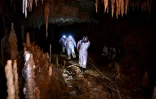 Des scientifiques de la DRAC de Nouvelle-Aquitaine se fraient un chemin sur un sentier étroit lors de leur progression dans la grotte de Cussac, lors d'une visite exclusive, le 20 février 2025 au Buisson-de-Cadouin, en Dordogne