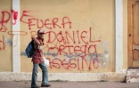 Un homme âgé passe devant un slogan peint sur un mur à Masaya au Nicaragua, réclamant: "Dehors l'assassin Daniel Ortega", le 12 mai 2018