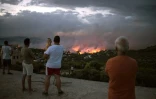 Des Grecs observent un feu de forêt à Rafina dans la banlieue d'Athènes, en Grèce, le 23 juillet 2018