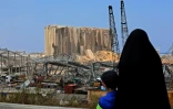 Une femme et un enfant regardent le 12 août 2020 à Beyrouth un silo à grains dévasté par les explosions
