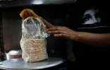 Un commerçant pèse un paquet de tortilla dans un point de vente ambulant à Mexico le 8 mai 2025
