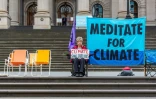 Une manifestante pour le climat tient une pancarte devant le Parlement de l'Etat de Victoria, le 7 octobre 2019 à Melbourne, en Australie