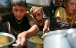Des Palestiniens attendent d'obtenir du riz auprès d'une soupe populaire dans l'ouest de la ville de Gaza, le 28 août 2025