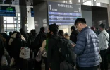 Des voyageurs font la queue à côté d'un panneau indiquant le train K27 à destination de Pyongyang, à la gare de Pékin, le 12 mars 2026 en Chine
