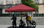 Des livreurs s'abritent du soleil sous un parasol à Madrid, le 18 juin 2025 lors d'une vague de chaleur en Espagne