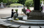 Une femme remplace des fleurs au Parc du mémorial de la paix à Hiroshima, le 26 mai