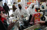 Des employés en pharmacie, en combinaison et masque de protection, servent des clients, le 25 janvier 2020 à Wuhan, épicentre du nouveau coronavirus